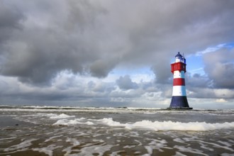 The lighthouse Roter Sand in front of blue sky with cumulus clouds and surf waves, Weser estuary,