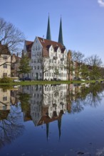 Historic house, towers of Lübeck Cathedral, trees, reflections on the surface of the water,