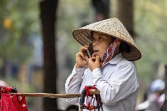 Woman with traditional straw hat making a phone call outdoors, A woman talking on the phone in the