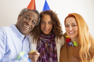 Three friends celebrate a special occasion, wearing colorful party hats and leis. Their joyful