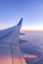A serene view from an airplane window showcasing the wing against a backdrop of a stunning sunrise