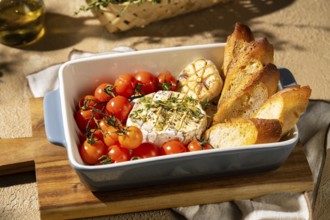 A savory dish featuring baked Camembert cheese garnished with herbs, surrounded by roasted cherry