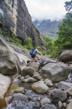 Female hiker jumping over rocks, Tugela Gorge or Tugela Gorge in the riverbed, Drakensberg National