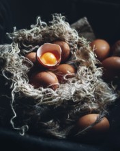 Close-up image of farm-fresh brown eggs nestled in a rustic, straw-lined nest. One egg is cracked