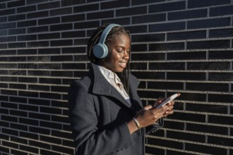 Side view of a young African American businesswoman with braids is seen enjoying a break, smiling