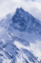 Fog envelops the snowy summit of the mountain Le Besso, Val d'Anniviers, Valais Alps, Canton