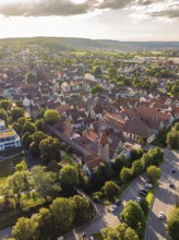 View of a historic old town with dense roofs, towers and surrounded by green trees and streets,