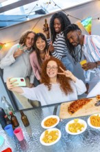 Vertical photo of a group of multi-ethnic friends gesturing success while taking selfie during