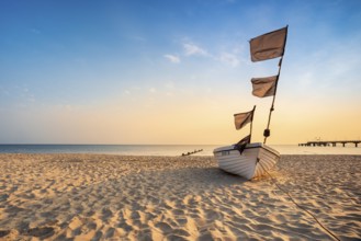 Fishing boat with black flags on a fine sandy beach in the morning light, Baltic resort Bansin,