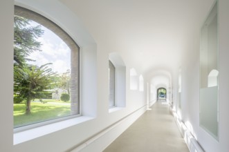 Bright corridor of hospital with arched windows fills with natural light, showcasing a serene