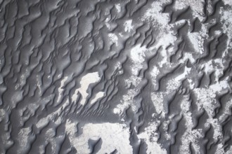 From above intricate patterns of black sand adorned with subtle white shades, creating a visually