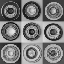 Monochrome plates and bowls with diverse geometric patterns form a striking arrangement in a grid.