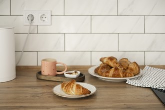 Delicious homemade croissants arranged on a rustic wooden table, captured alongside a warm cup of