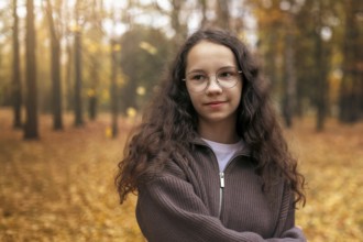 A teenage girl with curly hair enjoys a peaceful moment in an autumn forest, surrounded by golden