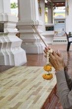 Bangkok, Thailand. February 20th 2025. A Thai visitor prays and makes an offering at The Wat Suthat