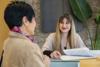 Client having a consultation with a smiling blonde receptionist, filling out documents and