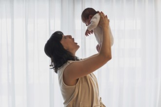 A joyful young mother holds her newborn baby lovingly in a softly lit room. This tender moment