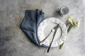 From above view of a stylish table setting featuring a white ceramic plate with blue dots, silver