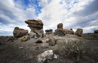 Eroded rock formations in volcanic landscape with dramatic cloudy skies, Ciudad Estratificada or