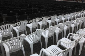 White plastic chairs standing in rows, seating at an open-air event, empty, vacant