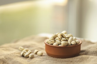 A warm image showcasing a bowl of pistachios on a burlap surface, with a soft focus background.