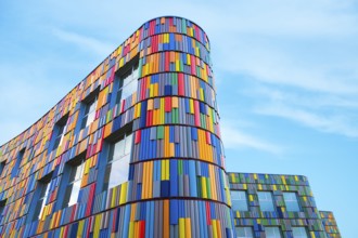 Low angle of a vibrant multicolor facade adorns a modern curved building, presenting a striking