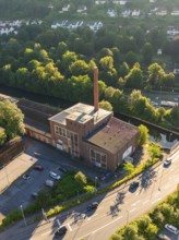 Aerial view of an industrial building on a street in a town with many trees and daylight, Calw,