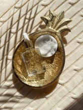A luxurious skincare cosmetic bottle with gold flakes beside a cotton pad, resting in an ornate