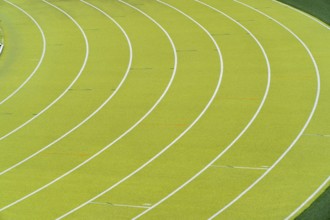 A vibrant aerial shot of a freshly marked bright green running track at an outdoor athletics
