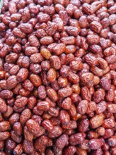 A vibrant close-up view of glossy, red jujube fruits, freshly harvested and displayed for sale at a