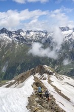 Mountaineer on a rocky ridge with snow, descent from the summit of Schönbichler Horn, view of