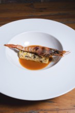 Juicy grilled prawn served on a bed of herb-seasoned egg terrine, accompanied by a flavorful orange