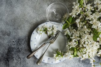 A table setting features vintage cutlery on a patterned plate, adorned with delicate white blossoms
