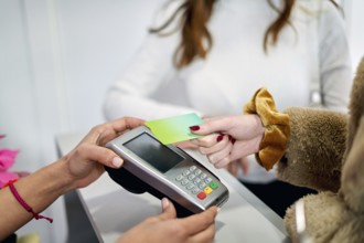 A client at a beauty salon completes a payment transaction by tapping a card on a device. The
