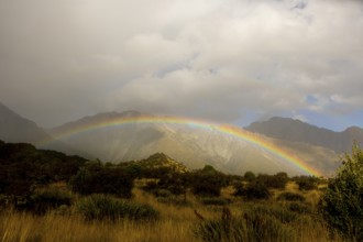 A breathtaking autumn scene at Mount Cook, New Zealand, featuring a vibrant rainbow arching over
