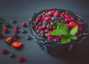 Mix of fresh berries, in a basket, on a wooden gray table, no people, top view