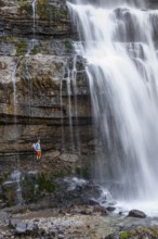 Little hiker in front of large Cascata di Mezzo waterfall, long exposure, Vallesinella, Brenta,