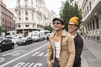 A joyful colombian gay couple enjoying a casual city walk. Both are wearing sunglasses and