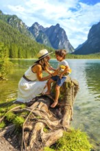 Mother and son sharing a playful moment by an alpine lake, surrounded by the breathtaking scenery