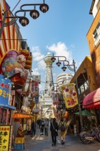 Lots of colorful signs in a pedestrian zone with shops and restaurants, behind Tsutenkaku Tower,