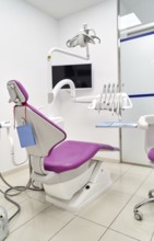Bright and clean dental clinic room featuring a modern dental chair, overhead light, and essential