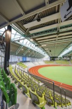 Interior view of an empty stadium with green rows of seats and an athletics track, Glaspalast,