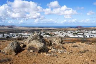 View of town, white houses of Teguise with church tower in dry volcanic landscape, view from