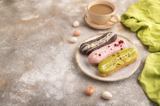 Glazed Eclairs on brown concrete background and green linen textile, cup of coffee, side view, copy