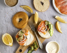 A top down view of a sesame bagel topped with creamy cheese, smoked salmon, cucumber slices, and