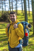 Male hiker carrying a backpack, enjoying a sunny day in the forest while trekking through the