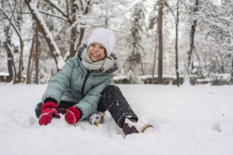 A cheerful child dressed warmly in a snowy forest, enjoying a winter day. The child wears a winter