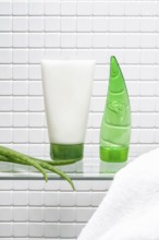 A refreshing display of a body care cream tube and a green aloe vera gel bottle, alongside a fresh