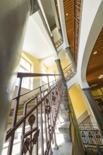 Historic staircase with arches and columns. Light falls through the windows, the structure looks