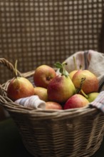 A charming wicker basket filled with ripe pears, resting on a striped textile. The warm tones and